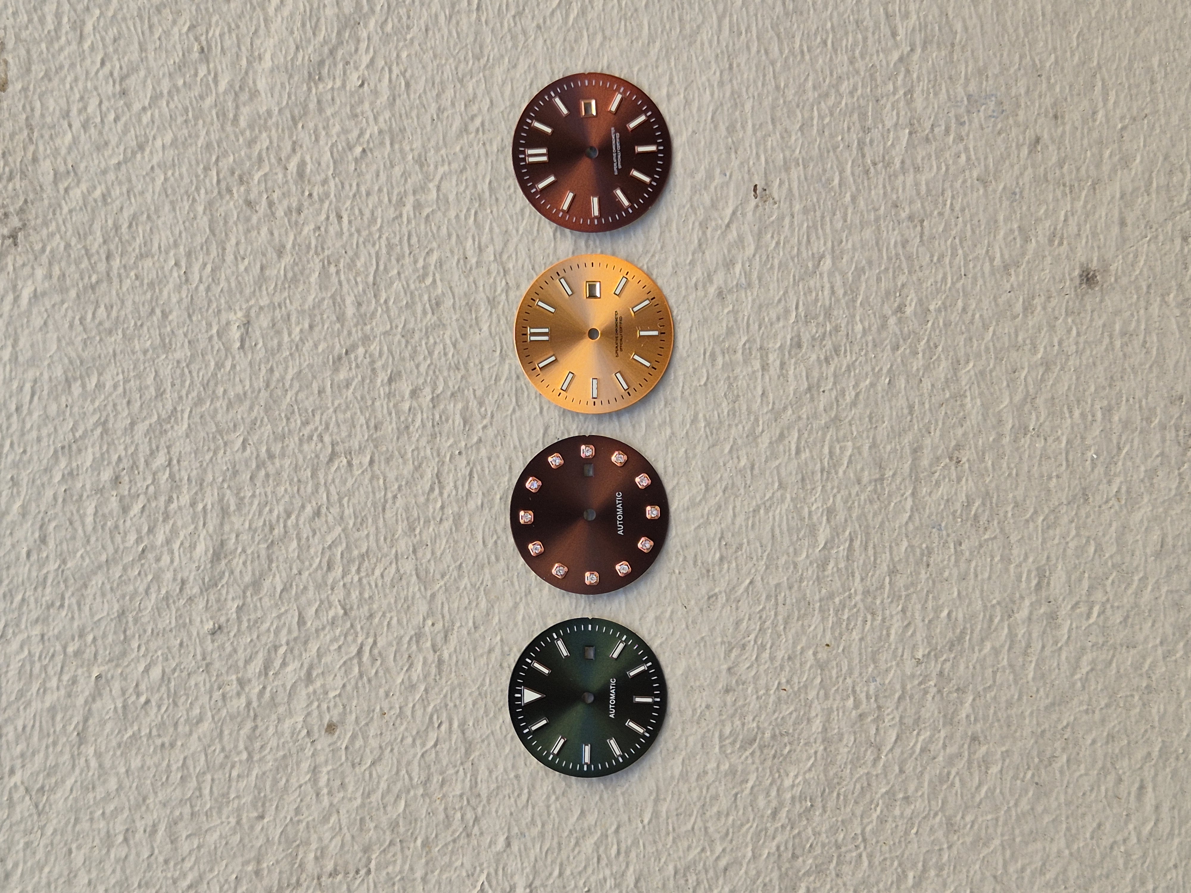 Four NH05 dials laid out vertically — burgundy sunburst, gold sunburst, brown with crystal indices, green sunburst